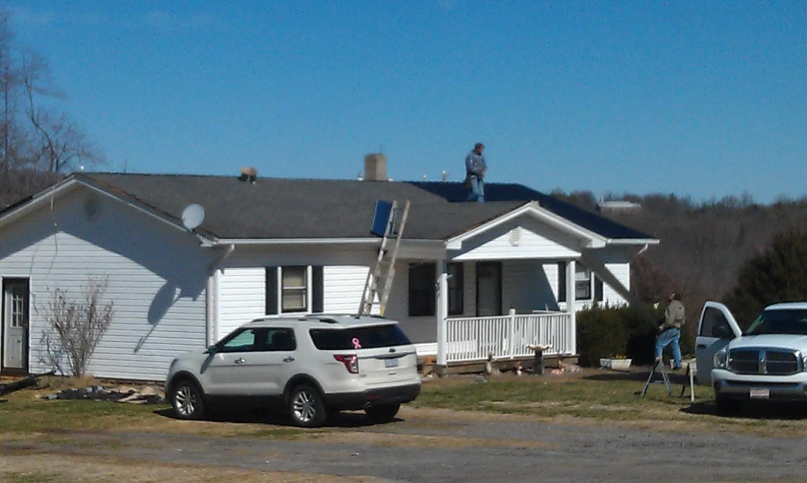 Roofers stripping shingles from a white ranch house roof in Easton