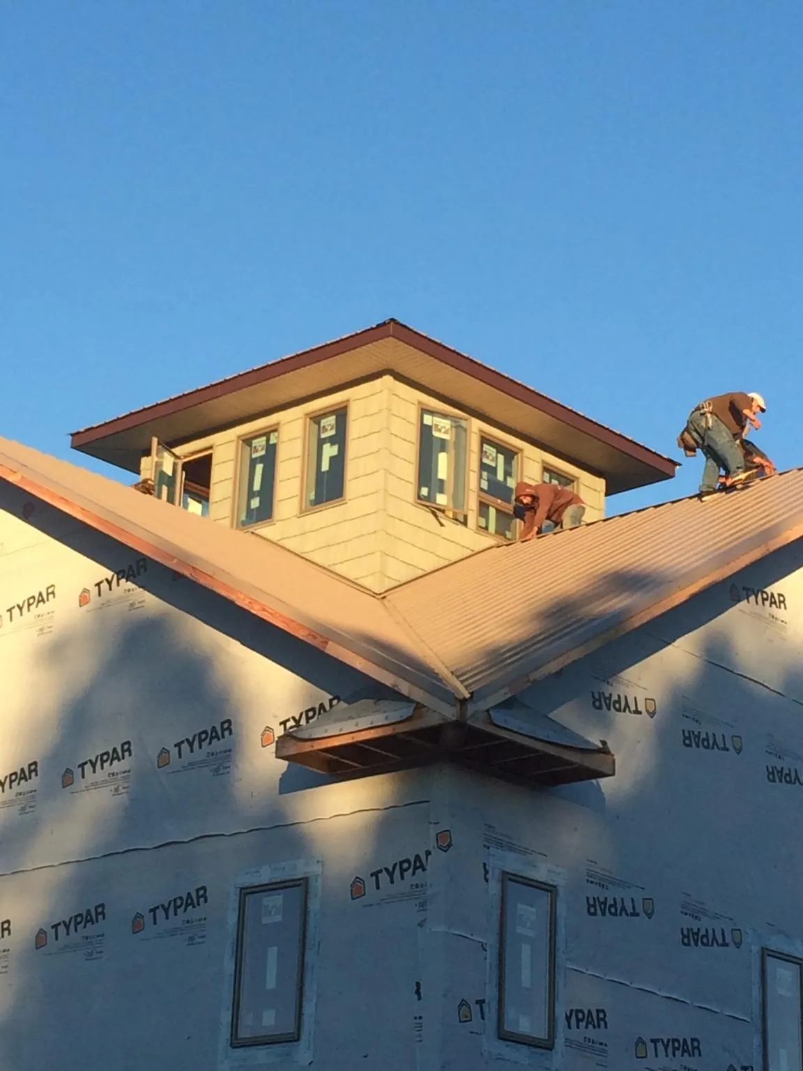 Roofers working around a rooftop cupola on a new metal roof at sunset — Roof Waterproofing in Easton by Roofing Brothers